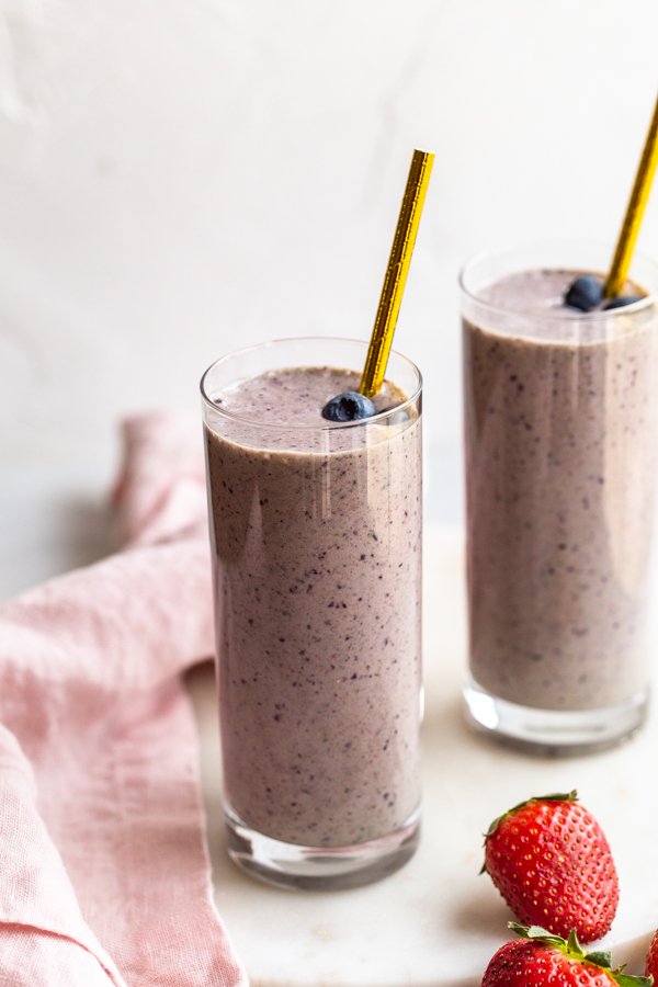 kefir smoothie glasses with a pink linen and strawberry on a marble counter