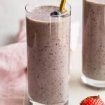 kefir smoothie glasses with a pink linen and strawberry on a marble counter