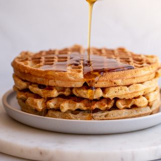 pouring syrup onto sourdough waffles