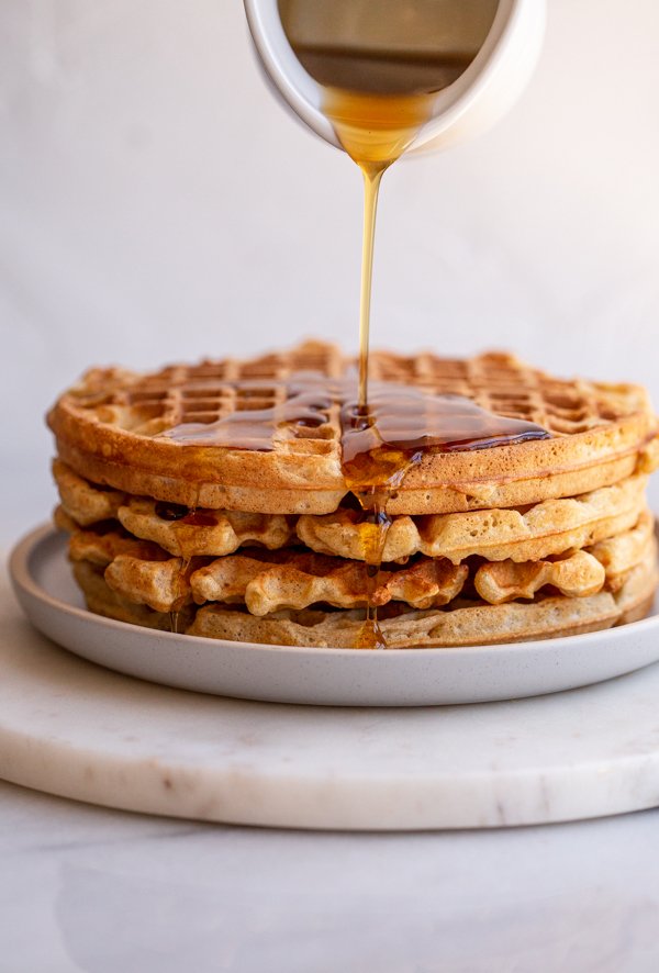 pouring syrup onto sourdough waffles