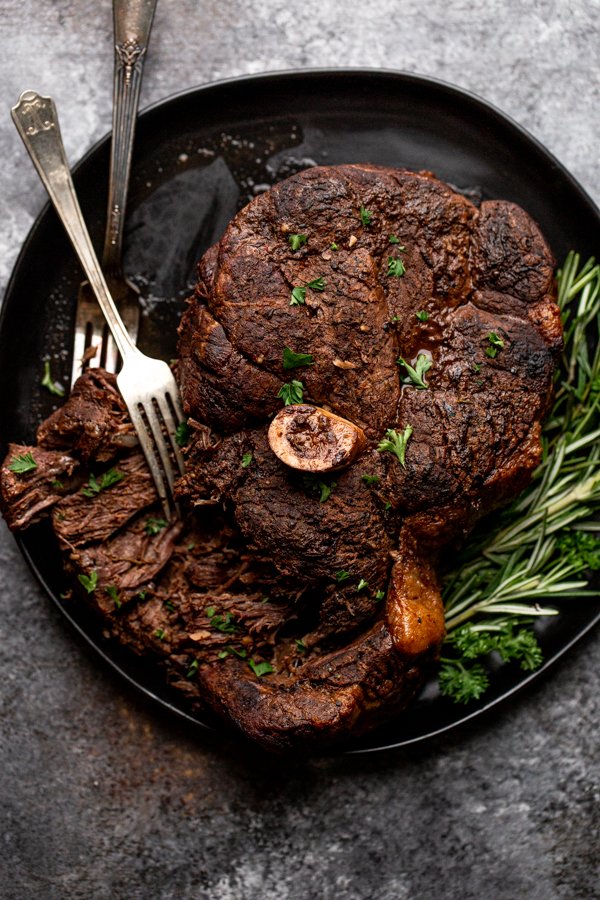 bear roast being torn apart with forks on a black serving platter