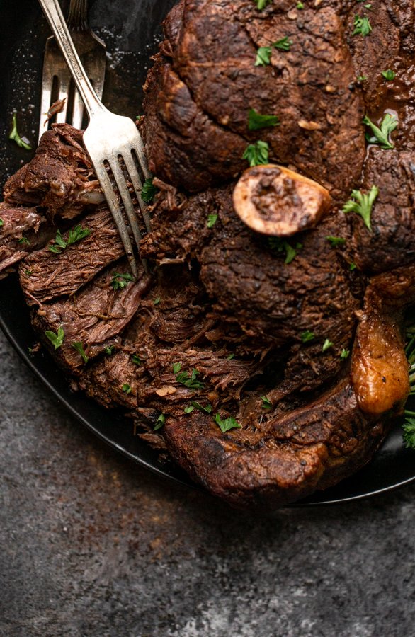 bear roast being torn apart with forks on a black serving platter