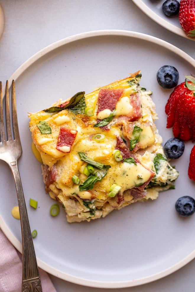 eggs Benedict casserole on a blue plate with fruit