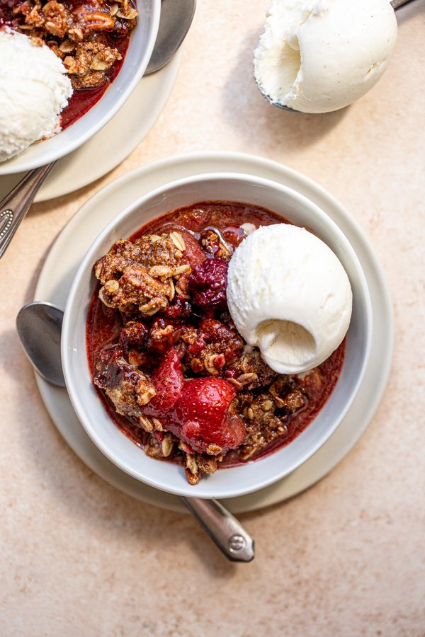 gluten free berry crisp with vanilla ice cream in a white bowl