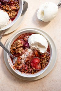 gluten free berry crisp with vanilla ice cream in a white bowl