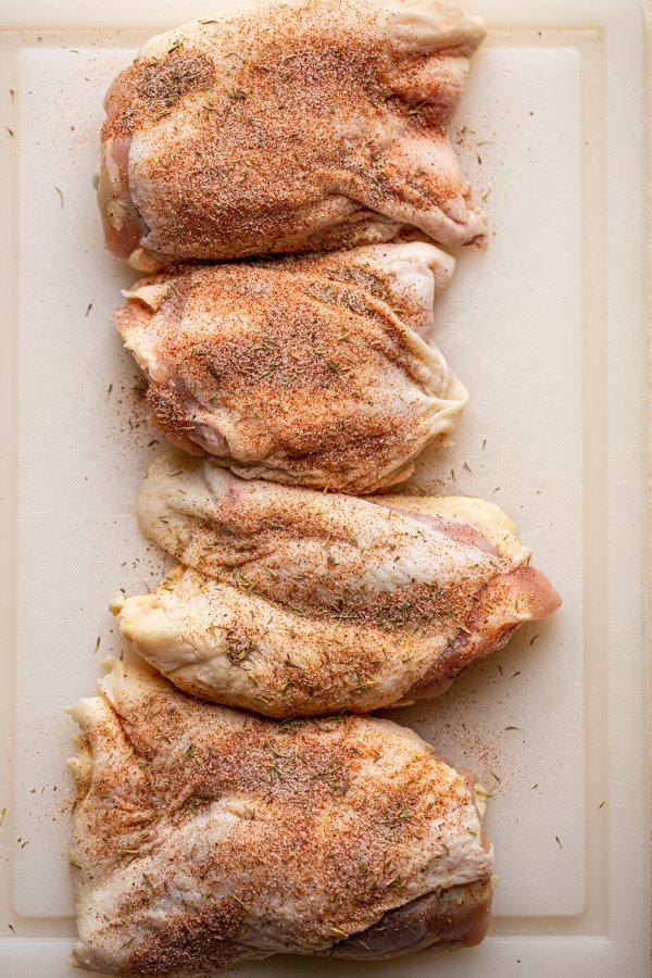 chicken thighs on a cutting board with seasoning