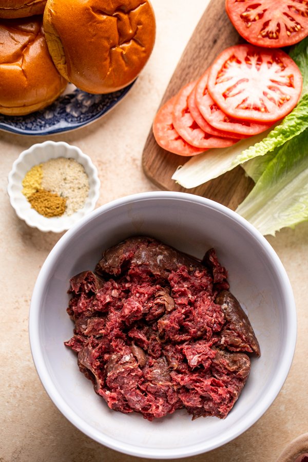 ground bear meat and burger fixings on a cream counter