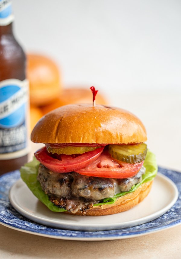 bear meat burger on 2 plates with a toothpick in it