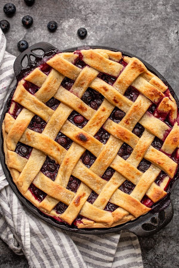 blueberry pie on a grey counter in a black pie dish