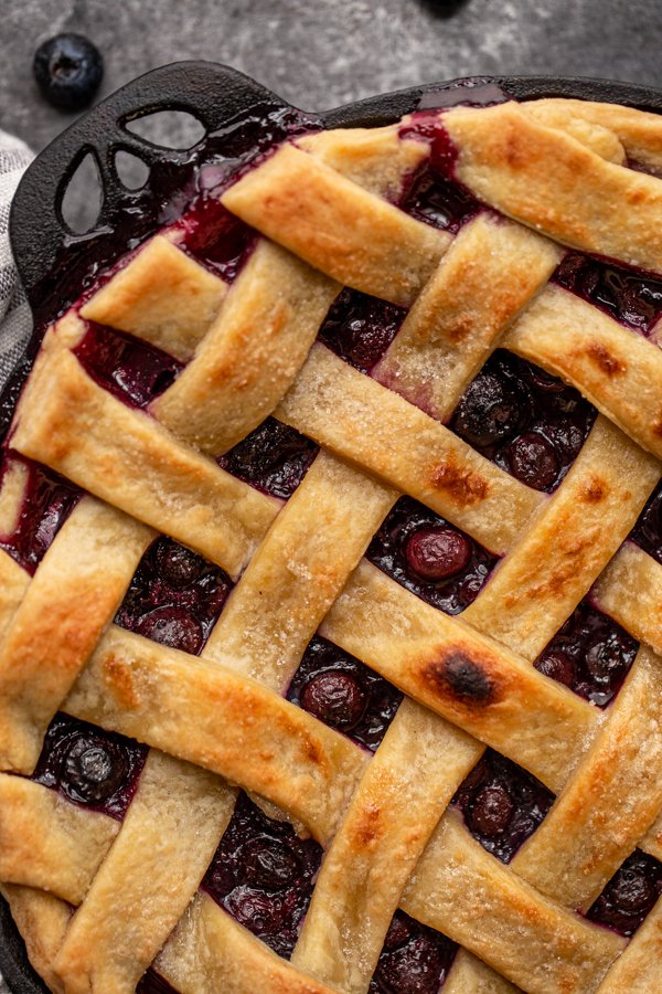 blueberry pie on a grey counter in a black pie dish