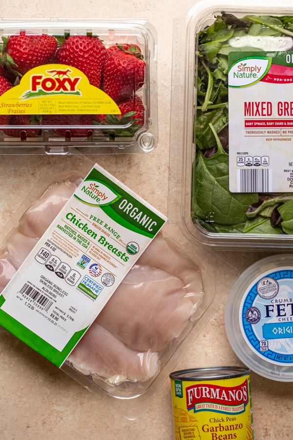 ingredients for grilled chicken and strawberry salad on a cream counter