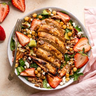 grilled chicken and strawberry salad in a bowl with a fork and a pink napkin