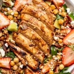 grilled chicken and strawberry salad in a bowl with a fork and a pink napkin