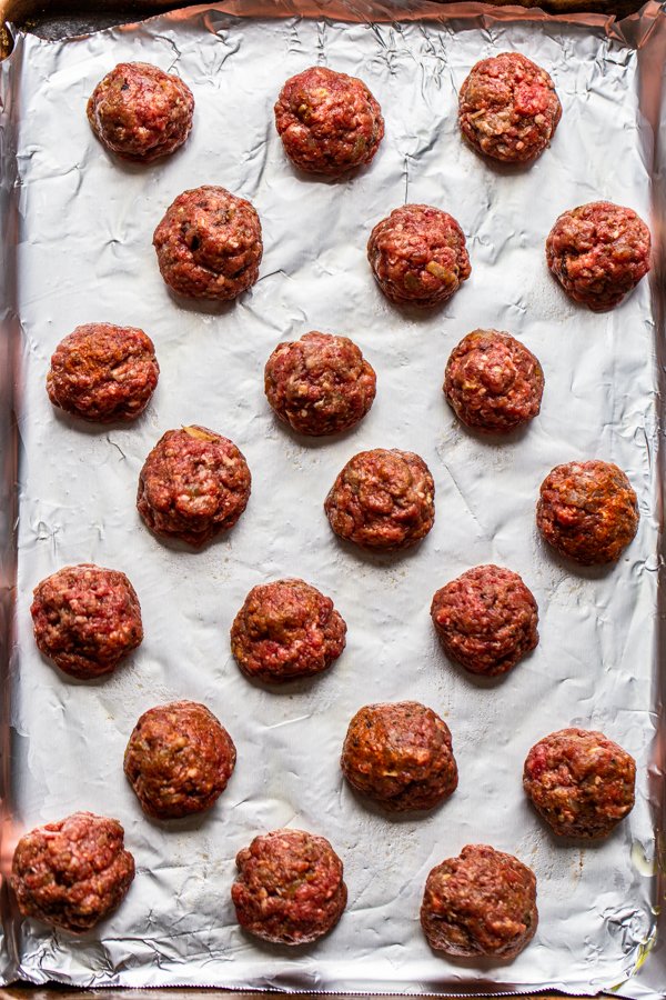 uncooked meatballs on a foil lined baking sheet