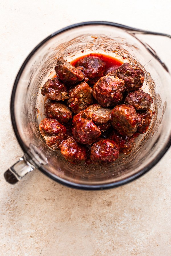 meatballs being tossed in a sauce in a bowl