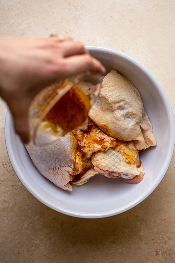 chicken thighs with marinade being poured on top