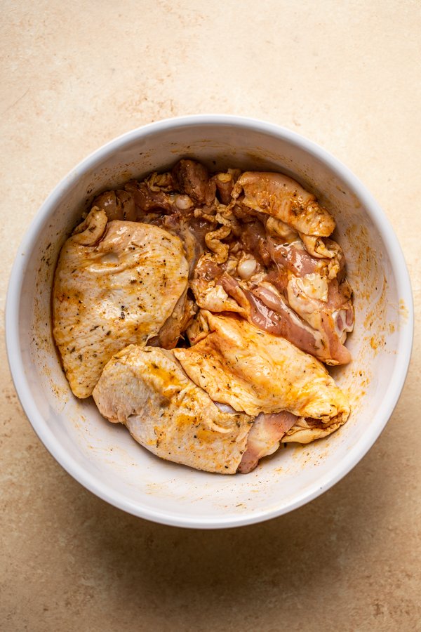 chicken thighs with marinade in a white bowl