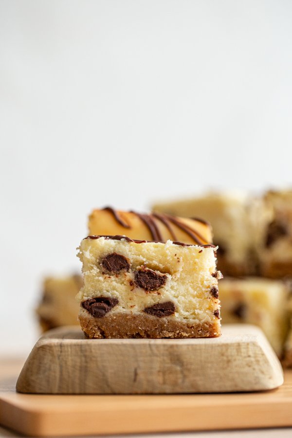 a chocolate chip cheesecake bar on a wood plate