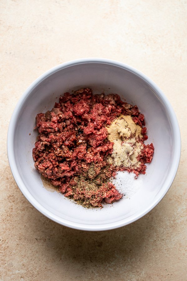 ground deer meat with seasoning in a white bowl