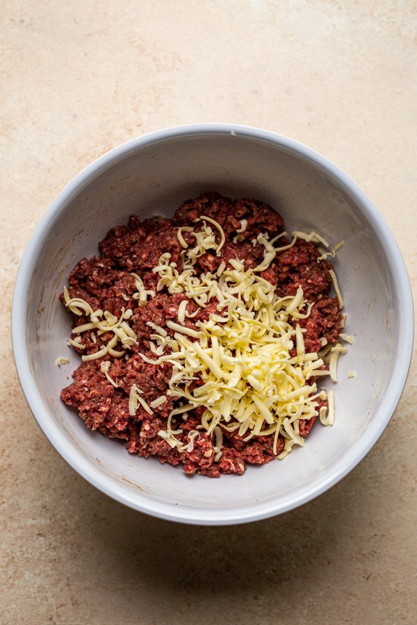 ground deer meat with grated butter with seasoning in a white bowl