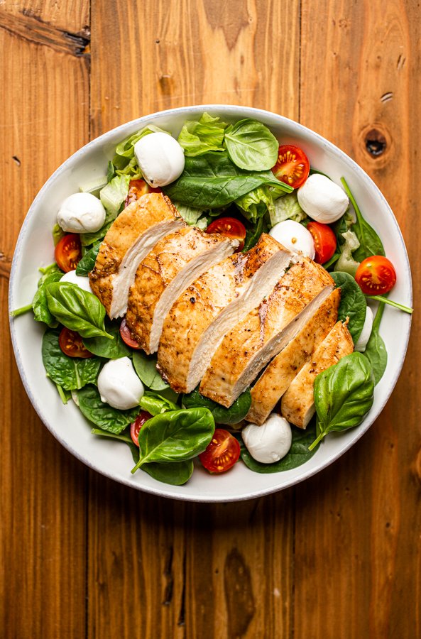 sliced chicken lettuce and tomato in a white bowl