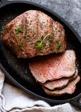 sliced venison steak on a black plate with a napkin