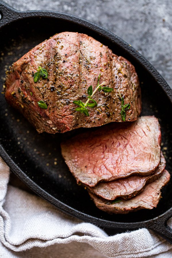 sliced venison steak on a black plate with a napkin