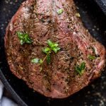 venison steak on a black plate with thyme leaves