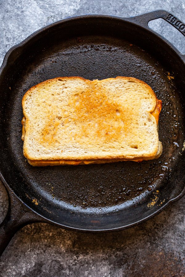 a grilled cheese cooking in a cast iron skillet