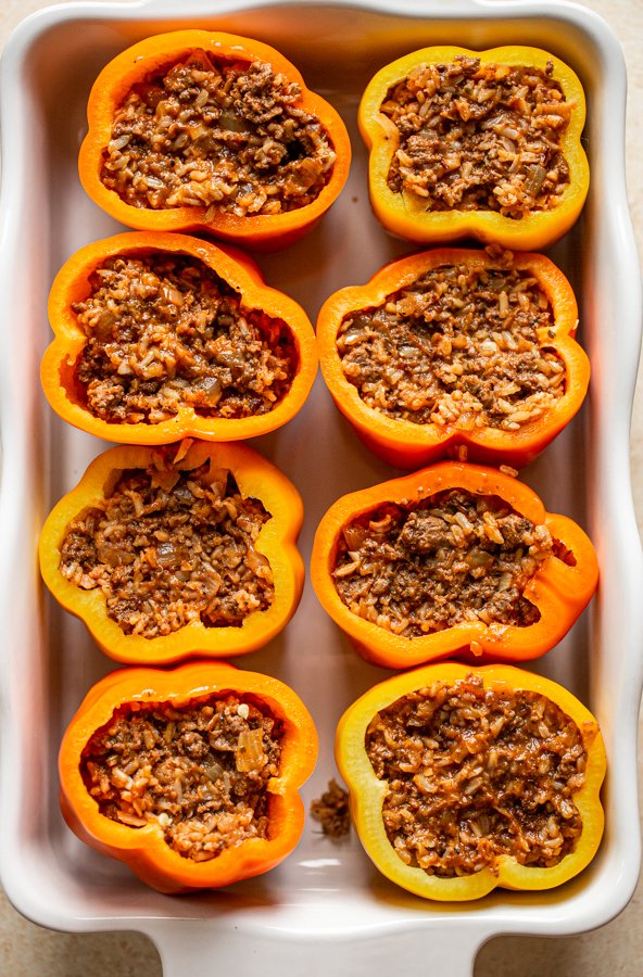 prepping stuffed peppers in a white baking dish