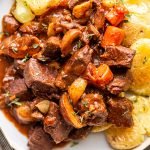 venison bourguignon on a plate with smashed potatoes.