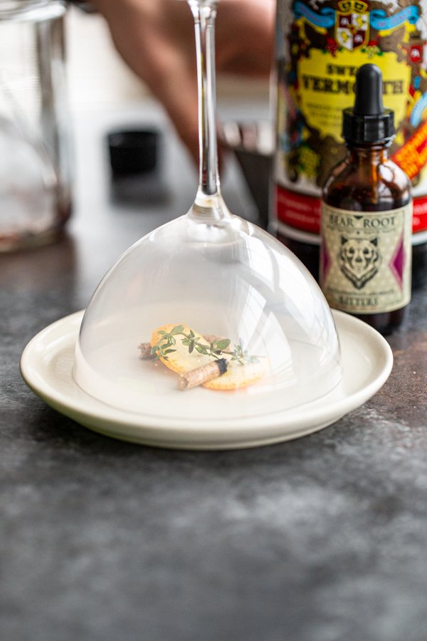 a manhattan glass over a smoking pellet