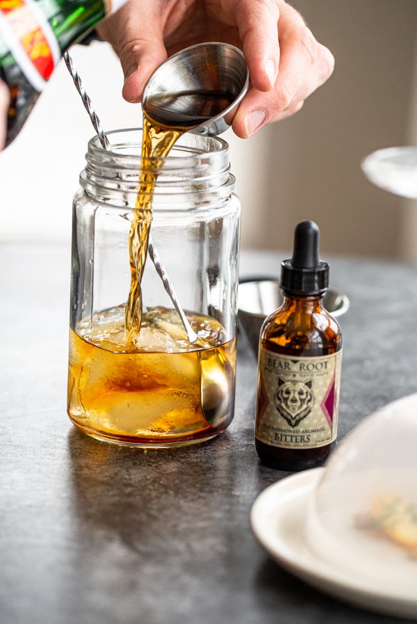 pouring whiskey into a a glass jar