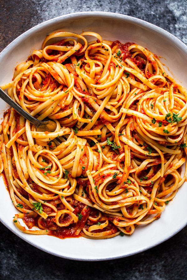 marinara sauce over pasta in a white bowl