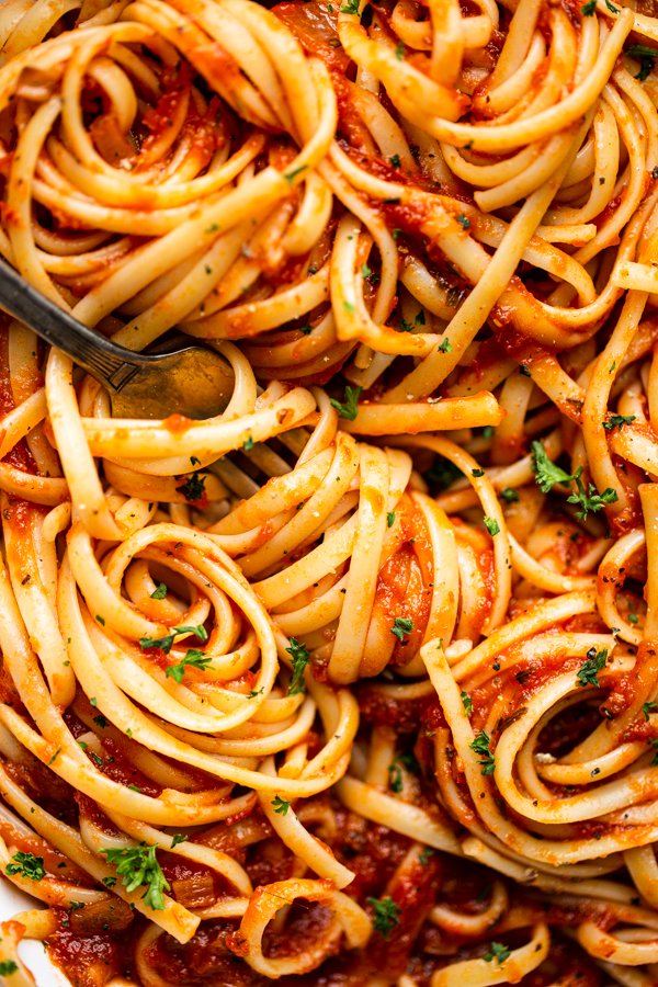 marinara sauce over pasta in a white bowl