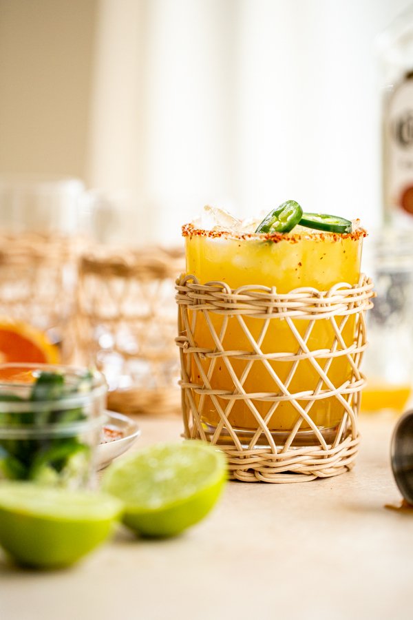 a jalapeno margarita in a rattan glass with a tajin rim