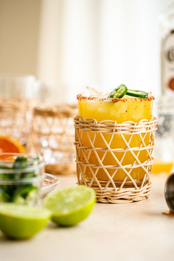 a jalapeno margarita in a rattan glass with a tajin rim