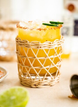 a jalapeno margarita in a rattan glass with a tajin rim