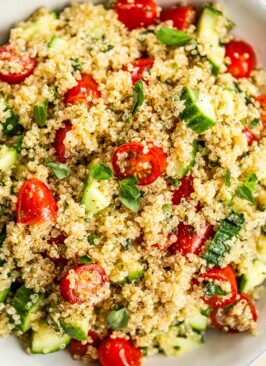 bowl of quinoa, chopped tomatoes, chopped cucumbers, and fresh herbs for the quinoa tabbouleh salad
