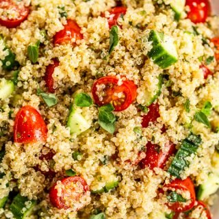 bowl of quinoa, chopped tomatoes, chopped cucumbers, and fresh herbs for the quinoa tabbouleh salad
