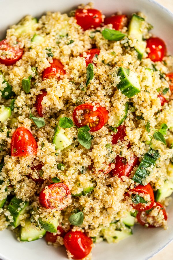 bowl of quinoa, chopped tomatoes, chopped cucumbers, and fresh herbs for the quinoa tabbouleh salad