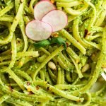 plated fettuccini with the radish pesto, a half of a lemon and three sliced radishes