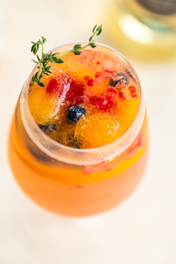 Rose Spritzer in wine class with fresh berries and rosemary sprig