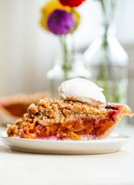 Slice of peach pie crumble topped with fresh whipped cream
