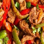 close up on venison cut into strips, sliced onion, red and green peppers sautéed with fajita seasoning topped with cilantro