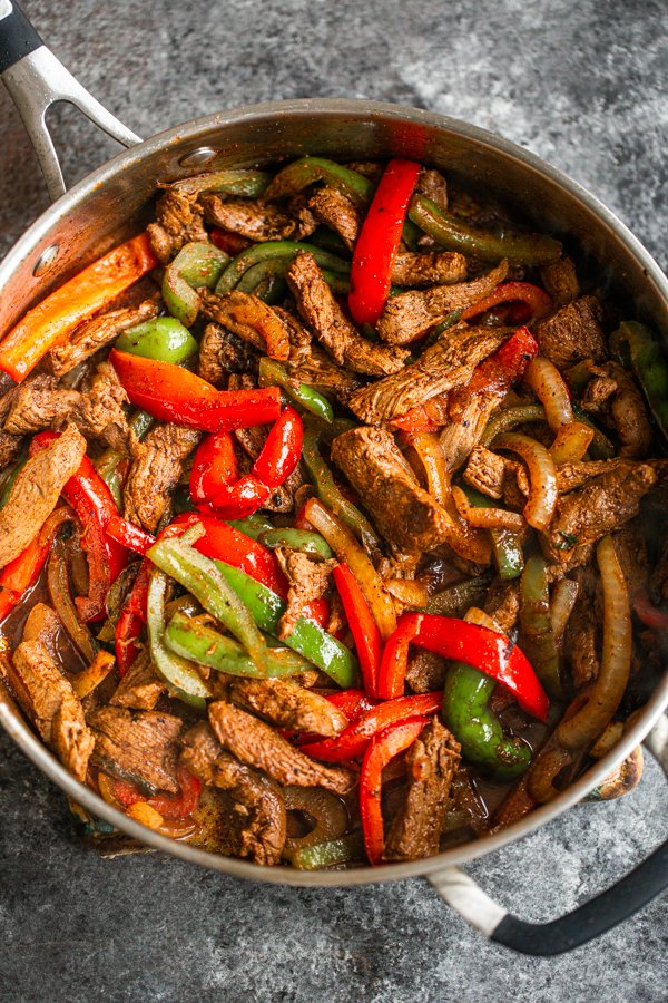 sliced venison steak, sliced onion, sliced red and green bell peppers sautéed in a pan with fajita seasoning