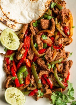 venison sliced in strips with sliced onion & red and green bell peppers, tortillas on the side and halved squeezed limes , topped with cilantro