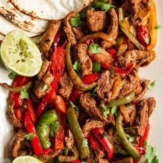 venison sliced in strips with sliced onion & red and green bell peppers, tortillas on the side and halved squeezed limes , topped with cilantro