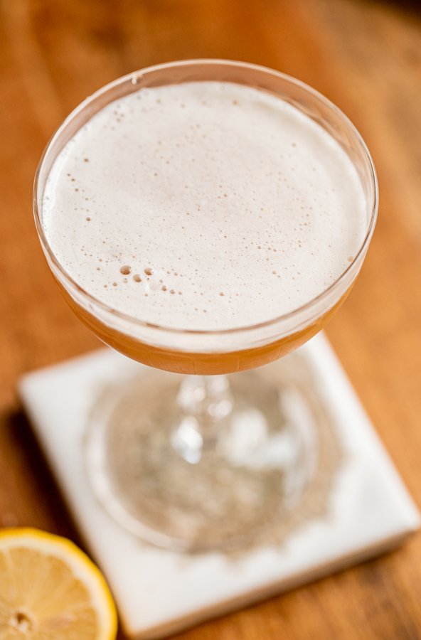 a frothy whiskey sour in a coupe glass