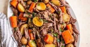 close up photo of venison roast, potatoes, and diced carrots topped with parsley